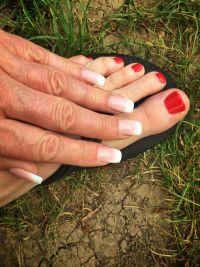 Klassisch rote Fußnägel und French Manicure an Händen Füsse